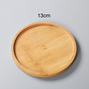 May include: A round, 13cm diameter, wooden coaster made of natural bamboo.