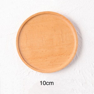 May include: A round, light brown wooden coaster with a diameter of 10 inches. The coaster is smooth and has a natural wood grain.