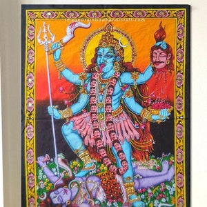 Può includere: Un arazzo colorato che raffigura la dea indù Kali, una divinità feroce e potente. Viene mostrata con più braccia, un corpo blu e una ghirlanda di teschi. Lei sta sopra il dio Shiva sconfitto, che giace a terra. L'arazzo è su uno sfondo arancione e giallo vibrante con dettagli floreali.