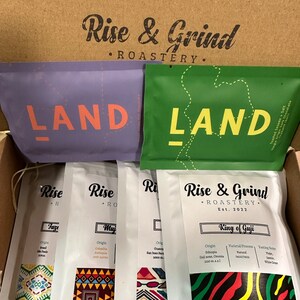 Puede incluir: Una caja con cuatro bolsas de granos de café de Rise & Grind Roastery. Las bolsas están etiquetadas con "Land" y presentan patrones geométricos coloridos. Los granos de café están etiquetados con "Faze", "Muj", "King of Guji" y "Rise & Grind".