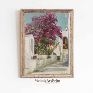 Puede incluir: Una pintura vintage de un edificio blanco con un patio. El patio tiene un gran árbol con flores rosas y una escalera de piedra que conduce a una puerta. La pintura está enmarcada en un marco de madera claro.