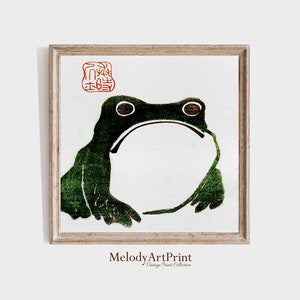 May include: A vintage Japanese woodblock print of a green frog with a red seal that says "本物" in Japanese. The frog is in a simple white frame.
