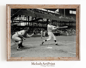 May include: A black and white photograph of a baseball game. A batter swings at a pitch while a catcher crouches behind home plate. The game is being played in a stadium with a large crowd in the background.