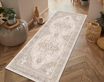 May include: A rectangular, beige and gray patterned rug with a detailed border. The rug features a central medallion design and is placed on a wooden floor. The rug is long and narrow, suitable for a hallway or entryway.