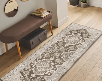 May include: A rectangular, patterned runner rug in shades of brown, beige, and cream. The rug features a central geometric design with intricate details and a border. The rug is placed on a hardwood floor.