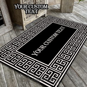 May include: A rectangular black and white rug with a Greek key border and the text "YOUR CUSTOM TEXT". The rug is placed on a wooden deck. The rug has a black center with white text.