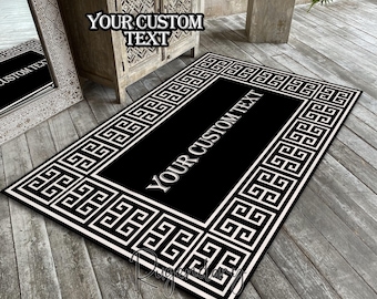May include: A rectangular black and white rug with a Greek key border and the text "YOUR CUSTOM TEXT". The rug is placed on a wooden deck. The rug has a black center with white text.