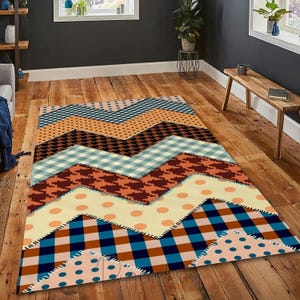 May include: A patterned area rug with a patchwork design. The rug features a chevron pattern with various geometric and dotted designs in shades of blue, orange, brown, and cream. The rug is placed on a wooden floor.