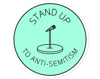 Op de afbeelding: Een ronde sticker met een lichtgroene achtergrond en een zwarte rand. De tekst "STAND UP TO ANTI-SEMITISM" staat rond een zwarte microfoongrafiek.