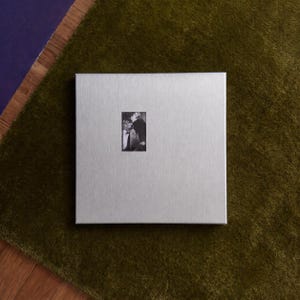 Square steel poster frame on green rug, flat lay view