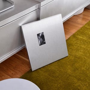 Square metal frame leaning against console table on rug
