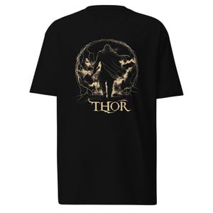 May include: Black t-shirt with a graphic of Thor, the Norse god of thunder, holding a hammer and standing in a circle of lightning. The text "THOR" is printed below the graphic.