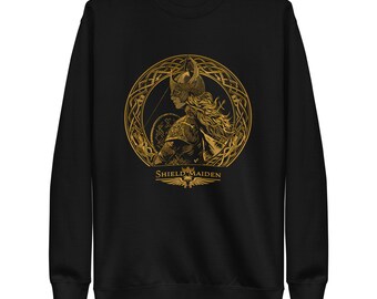 May include: Black sweatshirt featuring a gold illustration of a shield maiden in a circular design. The artwork includes a helmeted figure with a bow and arrow, and the text "SHIELD MAIDEN" below. The sweatshirt has long sleeves and a crew neck.