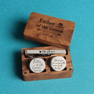 May include: Wooden box with a tie clip and cufflinks. The tie clip and cufflinks are engraved with the text "Father of the Groom" and the date "16.07.24".