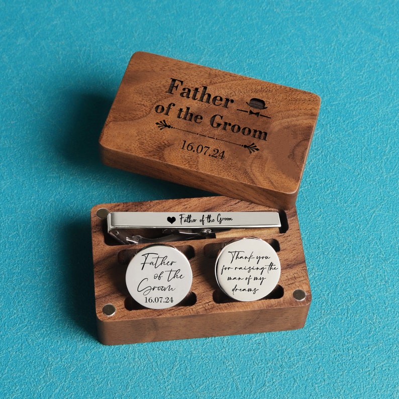 May include: Wooden box with a tie clip and cufflinks. The tie clip and cufflinks are engraved with the text "Father of the Groom" and the date "16.07.24".