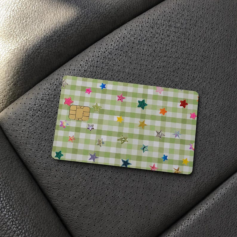 Puede incluir: Una tarjeta de pago rectangular con un patr&oacute;n de cuadros vichy en verde claro y blanco. La superficie est&aacute; decorada con numerosas estrellas peque&ntilde;as y multicolores en tonos rosa, azul, amarillo, naranja y verde. Se ve un chip met&aacute;lico dorado.