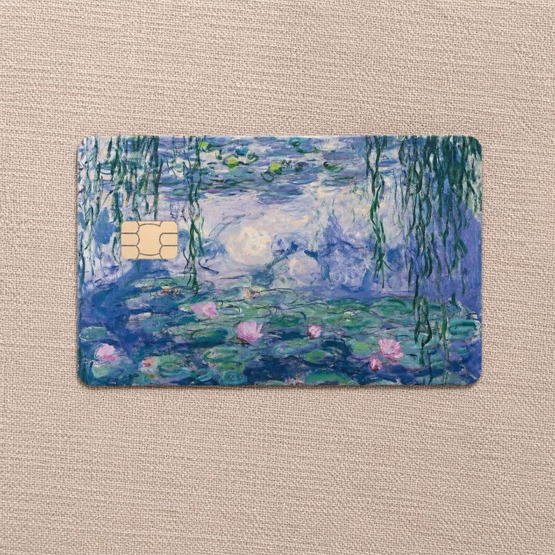 May include: A rectangular payment card featuring an impressionist painting of a water lily pond with weeping willow branches hanging from above. The artwork displays shades of blue, green, and pink, with a gold-colored metallic chip on the left side.