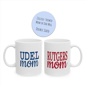 May include: Two white ceramic mugs with blue and red text. The mug on the left says "UDEL mom" in blue text. The mug on the right says "RUTGERS mom" in red text.  College-themed mom or dad mug, double-sided.