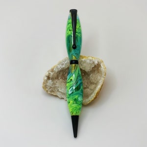 May include: A green and blue swirl pen with a black clip and black tip. The pen is resting on a white and brown rock.