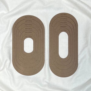 May include: Two sets of brown oval-shaped templates with concentric circles. The circles are labelled with measurements in inches. The largest circle in the set on the left is 14 inches by 7.5 inches. The largest circle in the set on the right is 15 inches by 8.5 inches.