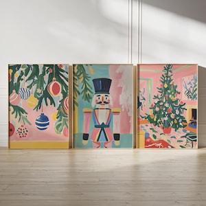 May include: Three framed illustrations of Christmas decorations. The first illustration shows a pink and green Christmas tree with ornaments. The second illustration shows a nutcracker in a red and blue suit. The third illustration shows a pink and green Christmas tree with ornaments.