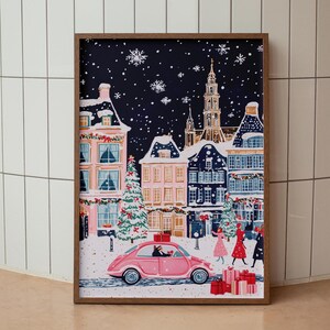 May include: A pink car drives through a snowy, nighttime town scene. The car is decorated with a red bow and has a dog in the passenger seat. The town is decorated with Christmas lights and snow is falling.