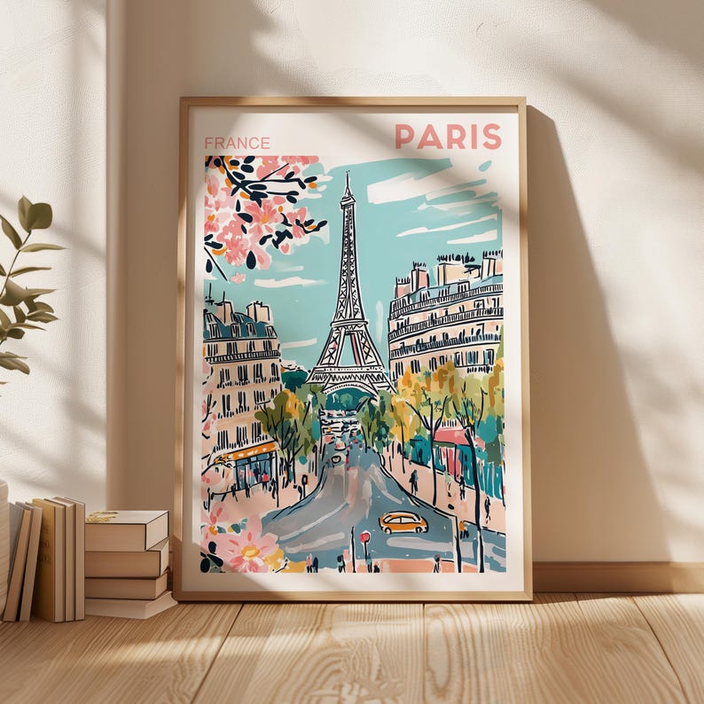 May include: A colorful illustration of the Eiffel Tower in Paris, France. The image features a blue sky with white clouds, pink cherry blossoms, and a street scene with cars and people. The text "FRANCE" and "PARIS" is printed on the poster.