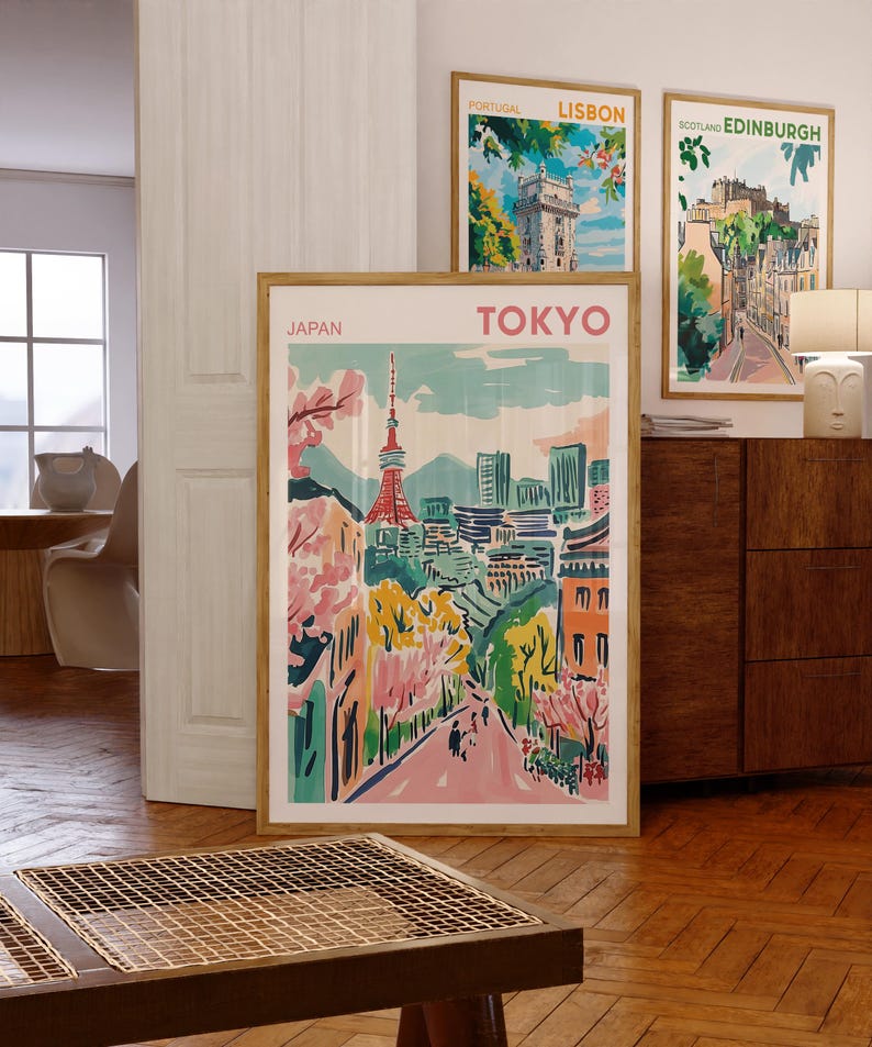 May include: Three framed travel posters with colorful illustrations of cityscapes. The posters are titled "Lisbon", "Edinburgh", and "Tokyo". The Tokyo poster features a pink and green cityscape with a tall tower in the center.