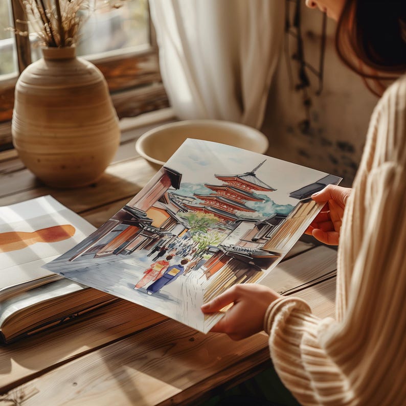 May include: A watercolor painting of a Japanese street scene featuring a red pagoda and traditional buildings. The artwork is held in front of a window, with a vase and bowl in the background. The painting depicts people in traditional clothing.