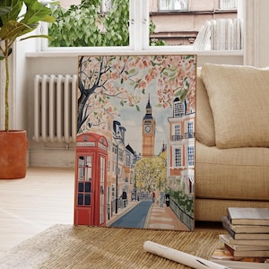 May include: A colorful illustration of a London street scene with a red telephone booth, a clock tower, and blooming cherry blossom trees. The street is lined with buildings and has a cobblestone road.