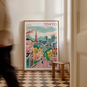 May include: A framed poster with a colorful illustration of Tokyo, Japan. The poster features a cityscape with a tall tower, trees, and buildings. The text "JAPAN" and "TOKYO" is printed at the top of the poster.