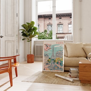 May include: A framed poster with a colorful illustration of the Eiffel Tower in Paris, France. The poster is hanging on a white wall in a living room setting.