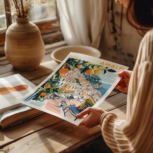 May include: A colorful illustration of the Amalfi Coast in Italy, featuring a cityscape with buildings, trees, and a blue ocean. The text "ITALY AMALFI" is printed in the top right corner.