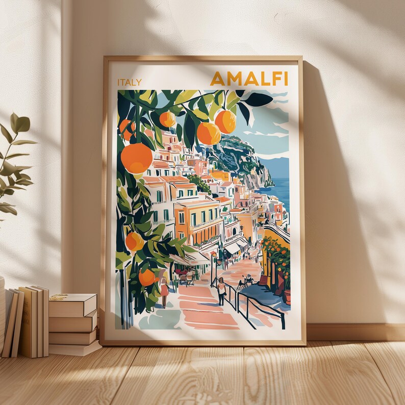 May include: A colorful illustration of the Amalfi Coast in Italy, featuring a hillside town with buildings in shades of yellow, orange, and pink. Lush green trees with orange fruit hang over the town, and a winding road leads down to the blue sea.