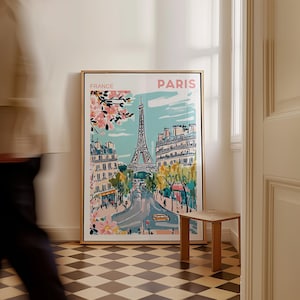 May include: A framed illustration of the Eiffel Tower in Paris, France. The illustration is in a colorful, cartoon style and features a blue sky, pink cherry blossoms, and a yellow car. The text "FRANCE" and "PARIS" is printed in pink at the top of the illustration.
