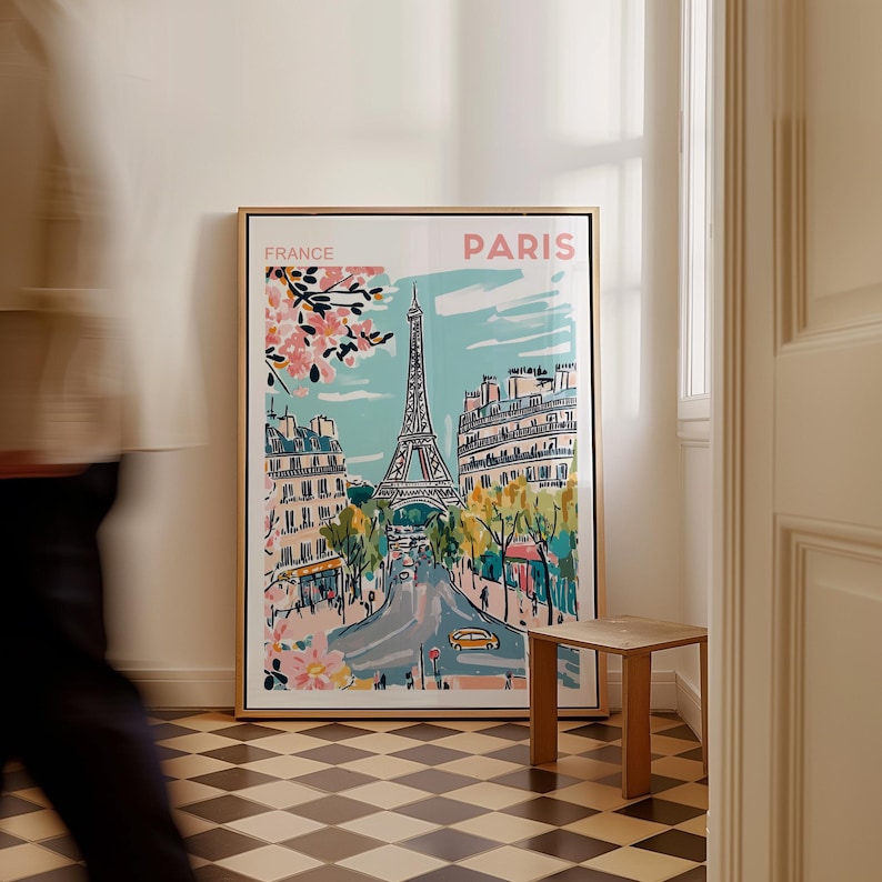 May include: A framed illustration of the Eiffel Tower in Paris, France. The illustration is in a colorful, cartoon style and features a blue sky, pink cherry blossoms, and a yellow car. The text "FRANCE" and "PARIS" is printed in pink at the top of the illustration.