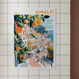 May include: A colorful illustration of the Amalfi Coast in Italy, featuring a hillside town with buildings, a winding road, and a lush orange tree with ripe fruit. The text "ITALY" and "AMALFI" are visible at the top of the image.