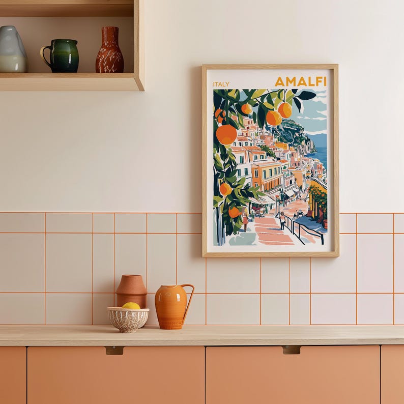 May include: A framed print of a colorful illustration of a coastal town in Italy with the text "ITALY AMALFI" at the top. The illustration features buildings, a winding road, and orange trees.