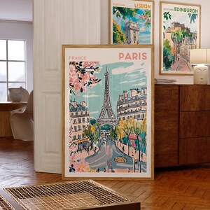 May include: A set of four framed cityscapes featuring illustrations of Lisbon, Edinburgh, Paris, and France. The Paris illustration features the Eiffel Tower and a street scene with pink cherry blossoms.