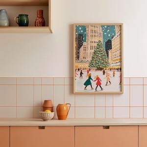 May include: A framed illustration of a snowy city scene with a large Christmas tree in the center. People are ice skating on a rink in front of the tree. The illustration is in a light blue, green, and red color palette.