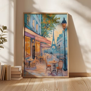 May include: A painting of a Parisian cafe with tables and chairs set up outside. The Eiffel Tower is visible in the background. The cafe is painted in a bright, colorful style with a blue sky and green trees. The painting is framed in a light wood frame.