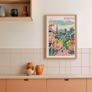 May include: A framed print of a colorful illustration of Tokyo, Japan. The print features a cityscape with a tower, trees, and buildings. The text "JAPAN" and "TOKYO" is printed at the top of the print.