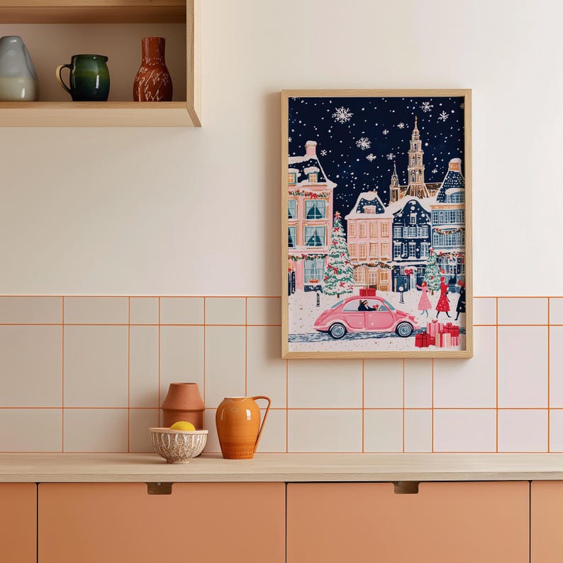 May include: A framed illustration of a snowy European town at night with a pink car driving through the street. The car is decorated with a Christmas tree and presents. The illustration is set against a dark blue background with white snowflakes.