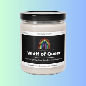 May include: A glass jar candle with a black lid and a label that reads "Whiff of Queer." The label features a rainbow and the text "burn brightly, love loudly, stay fabulous." The candle is 4 oz and made with 100% natural soy.