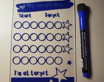 May include: A clear acrylic dry erase board with a blue heart and the text "My weight loss". The board has a section for "Start" and "Target" with rows of circles and stars. A blue dry erase marker is next to the board.