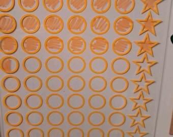 May include: A white board with the words "WEIGHT LOSS" written in black. There are 42 yellow circles with a peach colored center, and 8 yellow stars. The board also has the words "I'M AT TARGET" written in black.