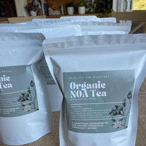 Puede incluir: Se muestran varias bolsas blancas de té Organic NOA. Cada bolsa tiene una etiqueta con el texto "Organic NOA Tea" y los ingredientes. El té se describe como un té nutritivo tradicional para el primer trimestre del embarazo y más allá.