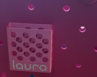 Puede incluir: Un bolso tote magenta con un organizador rosa a juego. El organizador tiene el nombre "laura" en letras blancas. El bolso tiene un asa y varios recortes circulares. El bolso está sobre una superficie de madera.