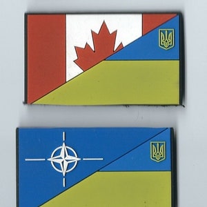 May include: Three rectangular patches with the flags of the United States, Canada, and NATO, each with a yellow and blue Ukrainian flag in the bottom right corner.
