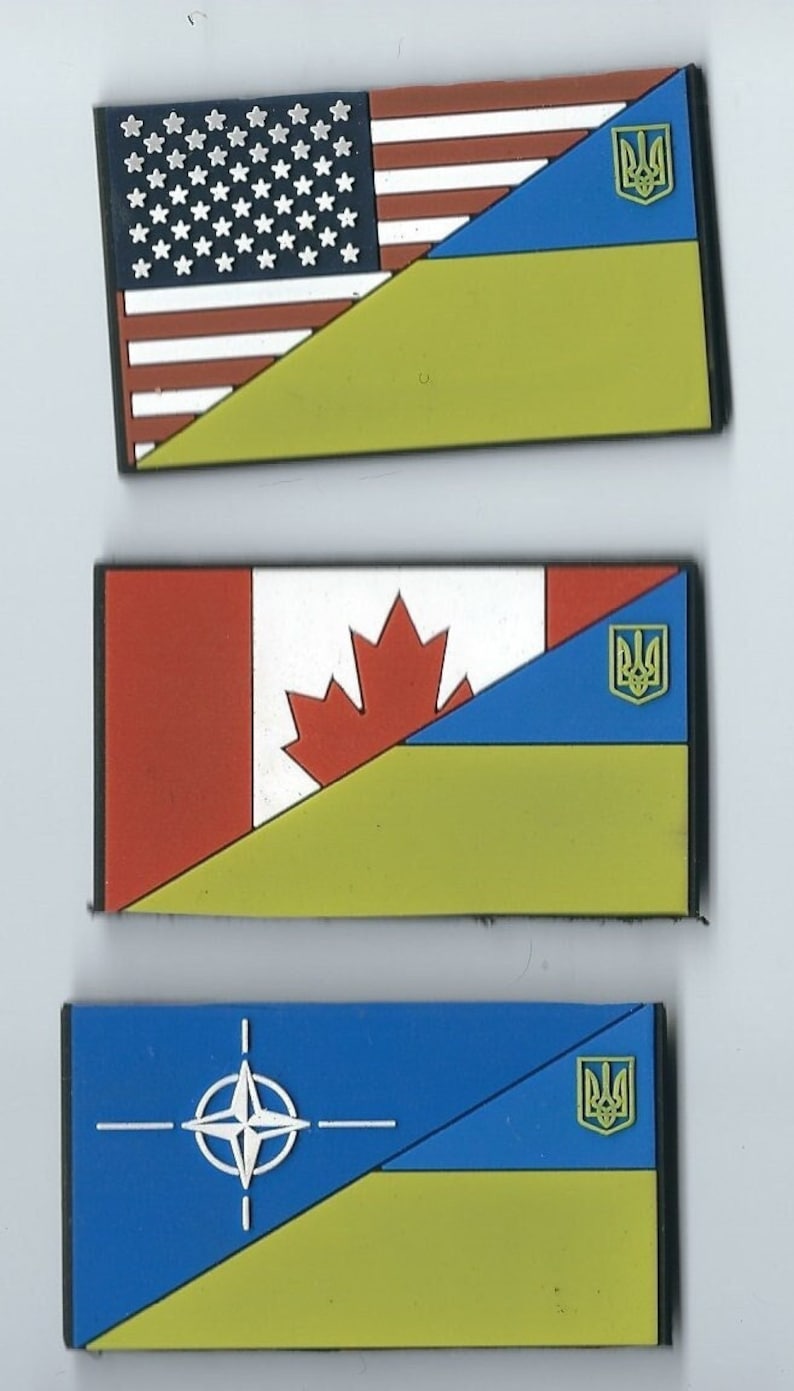May include: Three rectangular patches with the flags of the United States, Canada, and NATO, each with a yellow and blue Ukrainian flag in the bottom right corner.